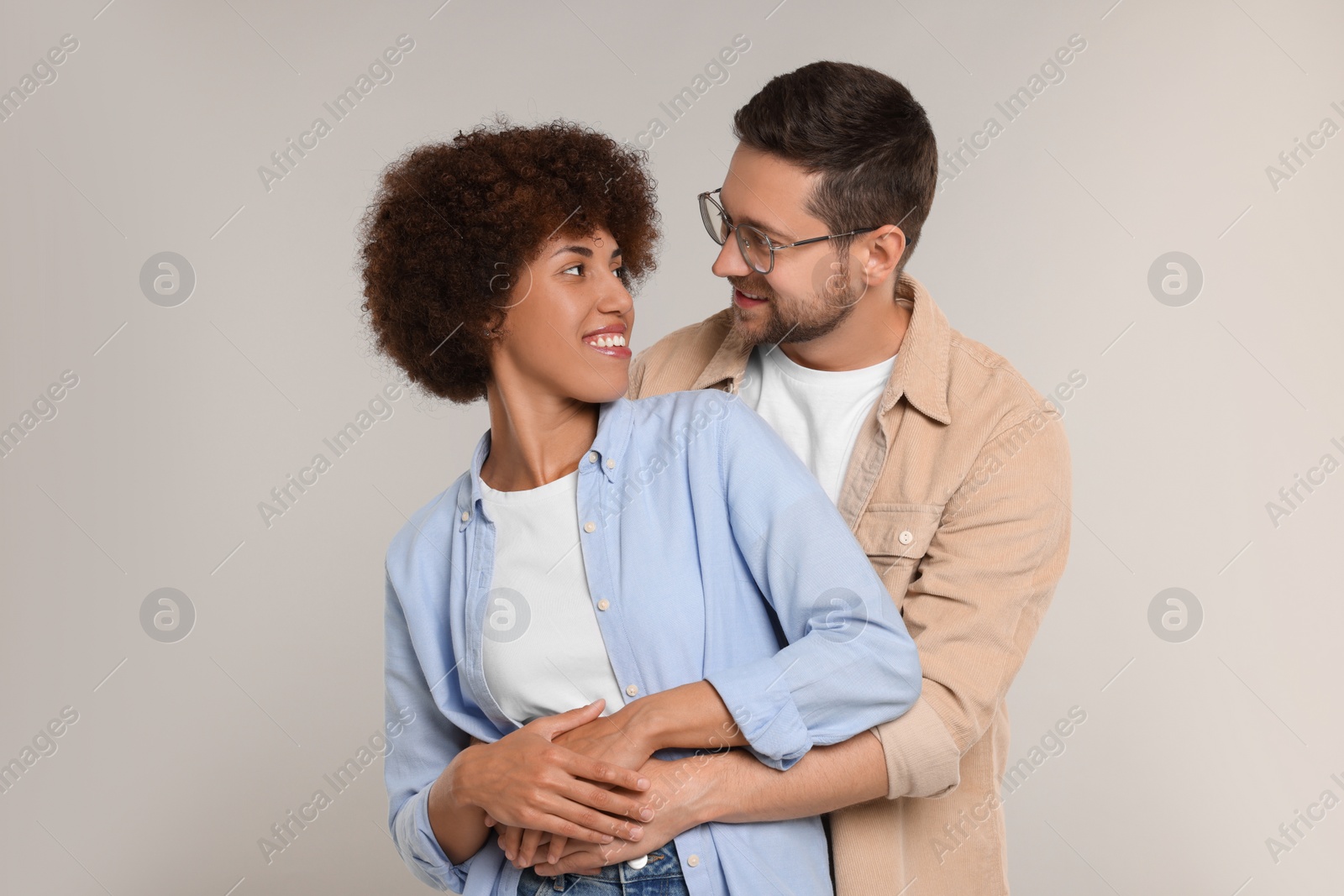 Photo of International dating. Happy couple hugging on light grey background