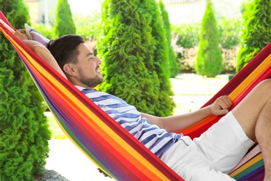 Photo of Man relaxing in hammock outdoors on warm summer day