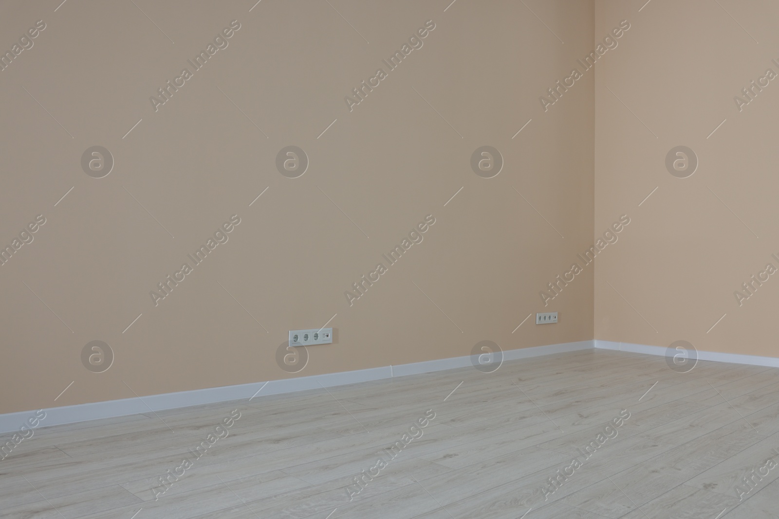 Photo of Pale orange walls with power outlet sockets in empty room