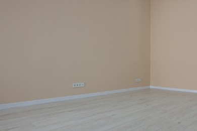 Photo of Pale orange walls with power outlet sockets in empty room