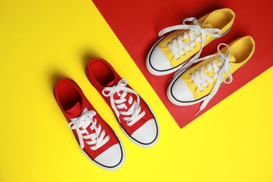 Red and yellow classic old school sneakers on color background, flat lay