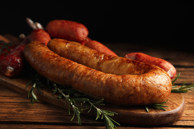 Different tasty sausages on wooden table, closeup