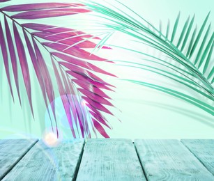 Image of Palm branches and blue wooden table against light background, color tone effect. Summer party