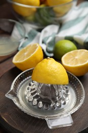 Photo of Glass squeezer and fresh lemons on wooden board
