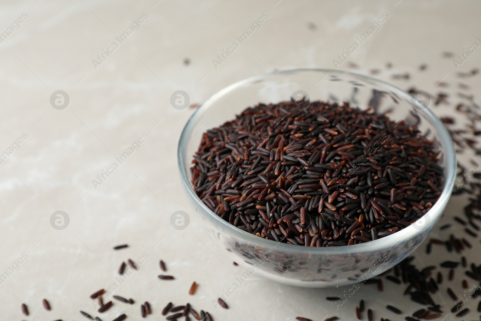 Photo of Uncooked brown rice in glass bowl on table