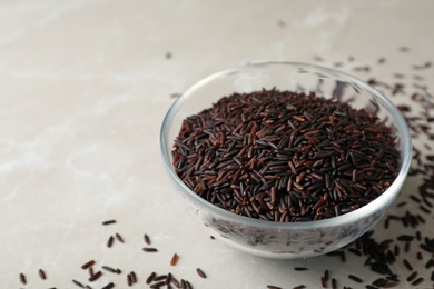 Uncooked brown rice in glass bowl on table