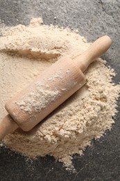 Photo of Scattered flour and rolling pin on grey textured table, top view