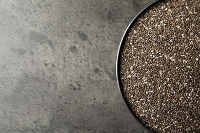 Bowl with chia seeds on grey table, top view. Space for text