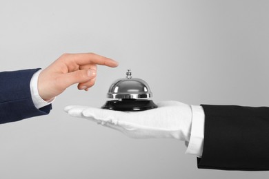 Photo of Man ringing butler service bell on grey background, closeup