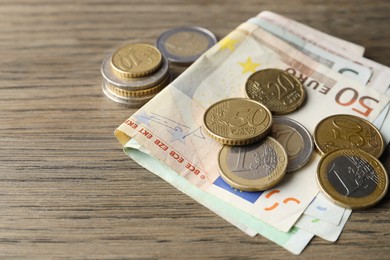 Photo of Euro banknotes and coins on wooden table, closeup