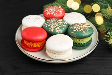 Photo of Different decorated Christmas macarons on black wooden table