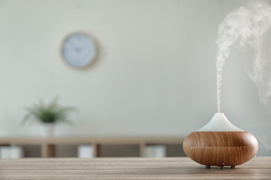 Photo of Modern aroma lamp on table against blurred background with space for text