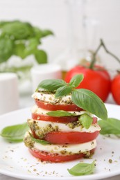 Photo of Plate of stacked Caprese salad with pesto sauce on table, closeup