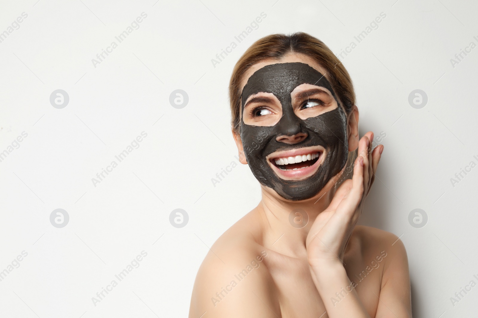 Photo of Beautiful woman with black mask on face against light background. Space for text