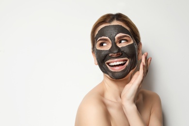Beautiful woman with black mask on face against light background. Space for text