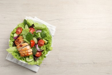 Photo of Delicious salad with chicken and vegetables on wooden table, top view. Space for text