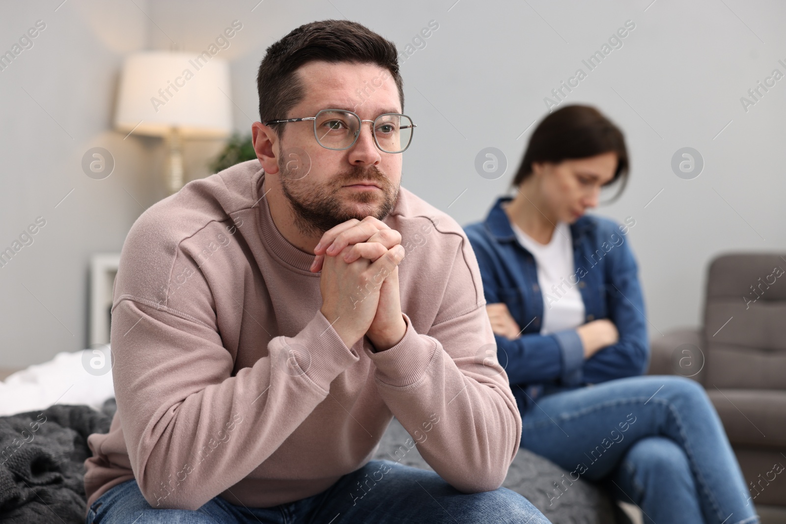 Photo of Offended couple ignoring each other after quarrel in bedroom, selective focus. Relationship problems