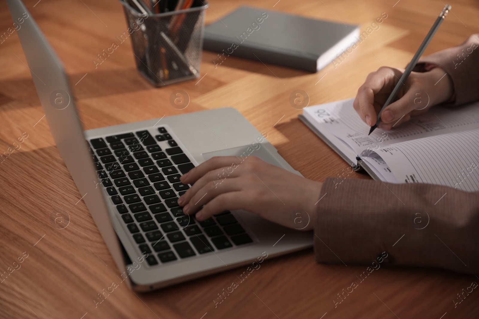 Photo of Woman working with laptop at wooden desk, closeup