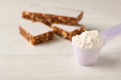 Photo of Scoop of protein powder and blurred cereal bars on background. Space for text