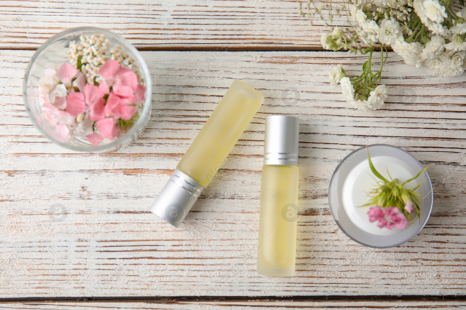 Photo of Flat lay composition with essential oils and flowers on wooden background