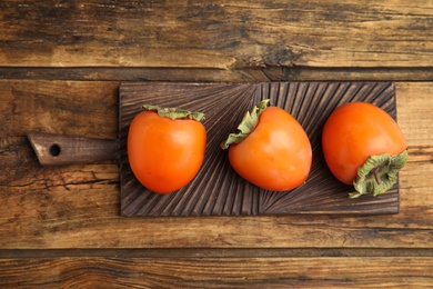 Photo of Tasty ripe persimmons on wooden table, top view