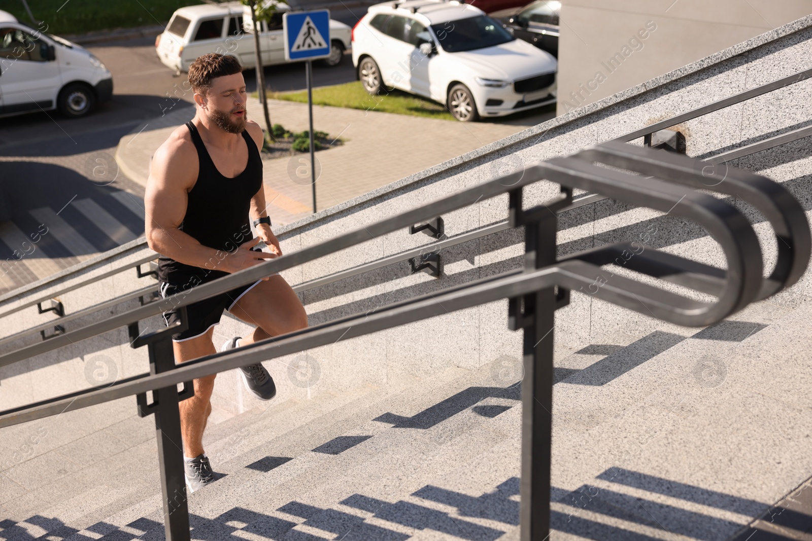 Photo of Man running up stairs outdoors on sunny day. Space for text