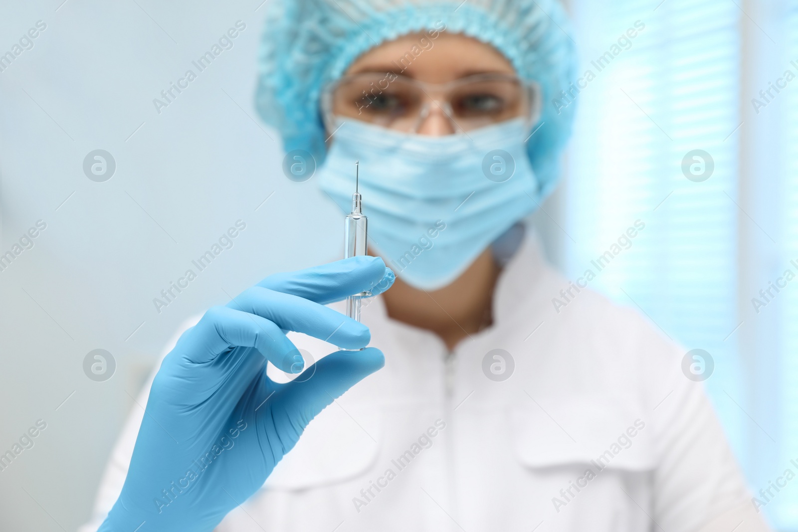 Photo of Doctor holding syringe with COVID-19 vaccine on blurred background