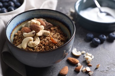 Photo of Tasty granola with nuts in bowl on gray table, closeup