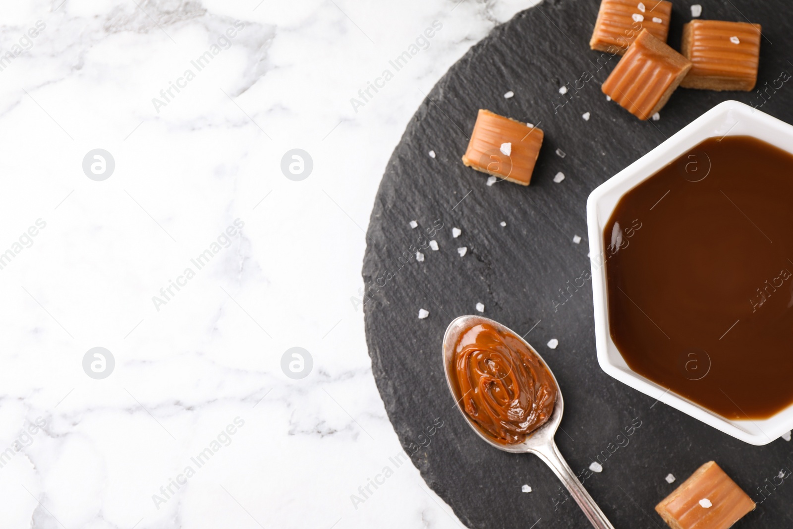 Photo of Salted caramel on white marble table, top view. Space for text