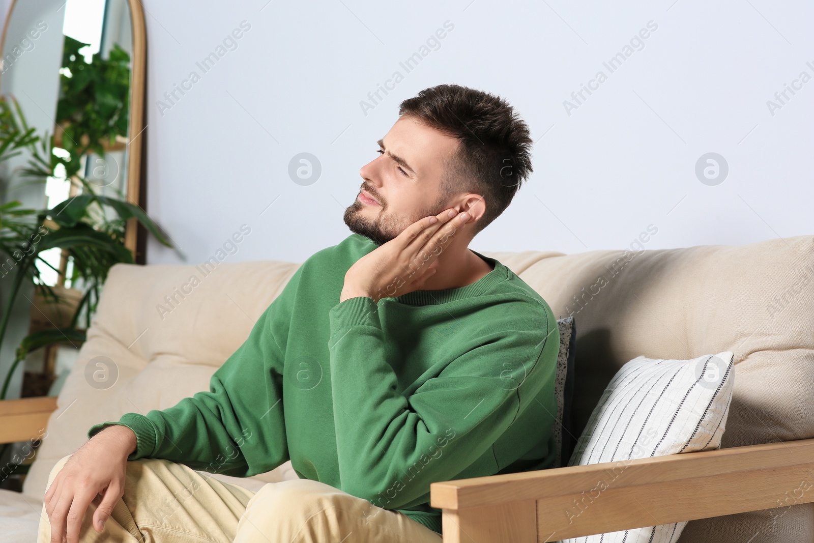 Photo of Young man suffering from ear pain at home