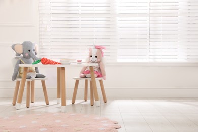 Photo of Cute toys at table with crockery indoors