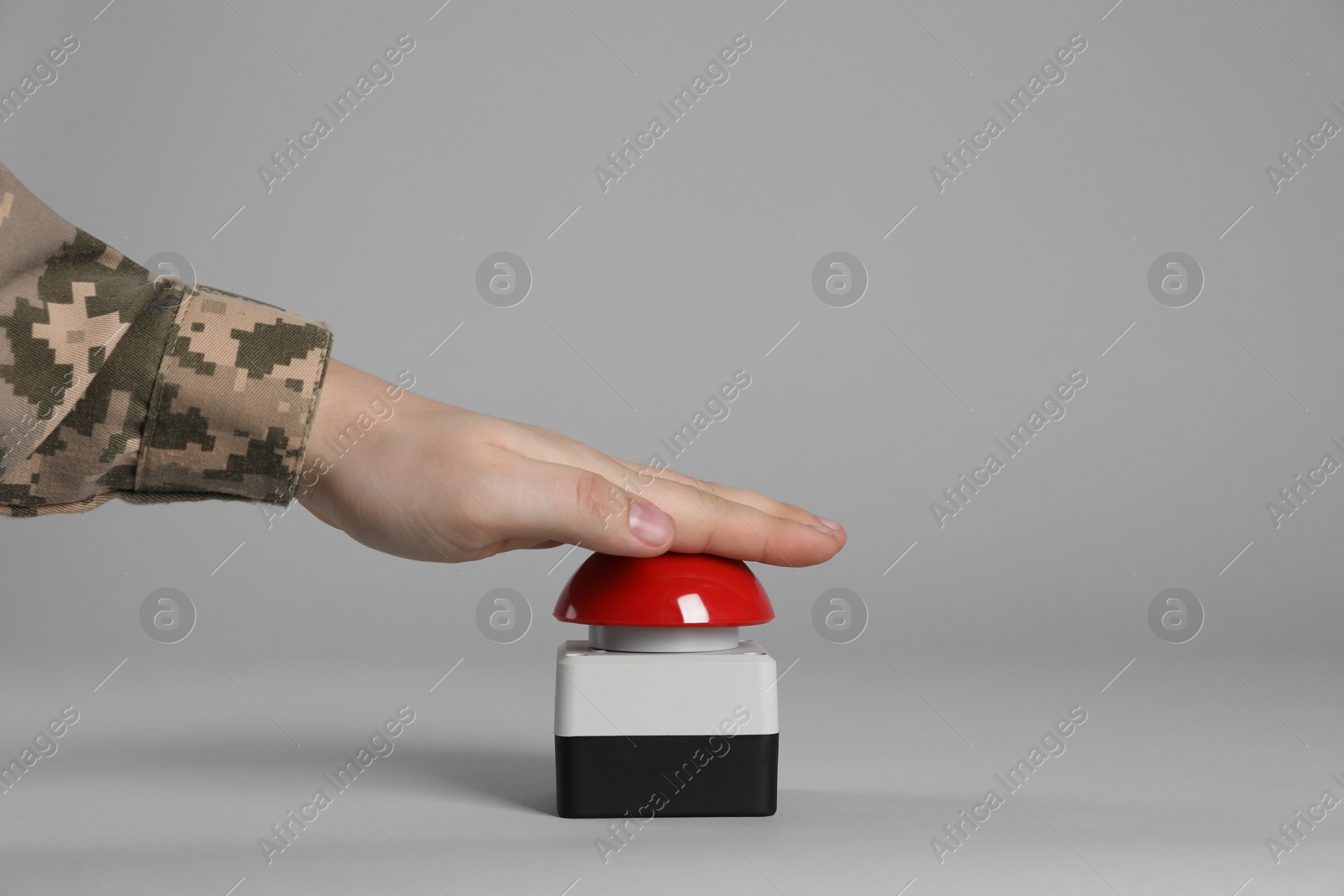 Photo of Serviceman pressing red button of nuclear weapon on light gray background, closeup. War concept