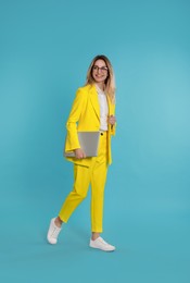 Photo of Young woman with modern laptop on light blue background