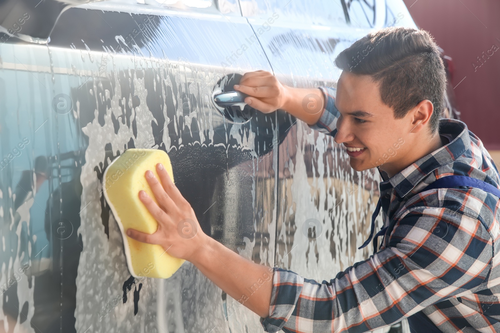 Photo of Worker cleaning automobile with sponge at car wash