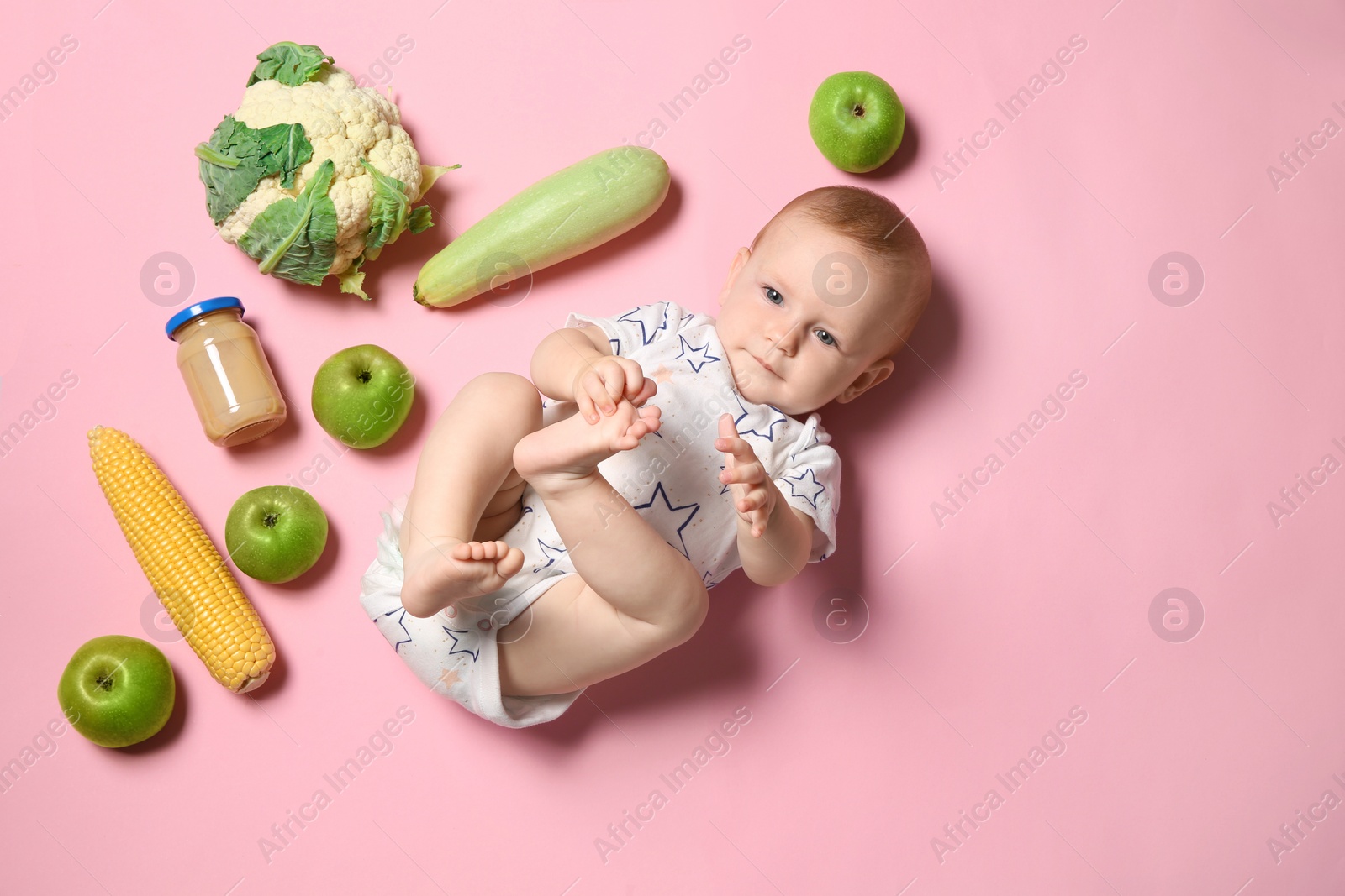 Photo of Cute little child with ingredients and puree in jar on color background, top view. Baby food