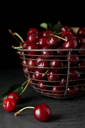 Photo of Sweet juicy cherries with water drops on black table