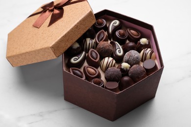 Open box of delicious chocolate candies on white marble table