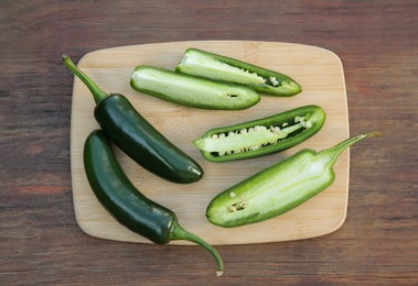 Photo of Fresh green jalapeno peppers on wooden table, top view