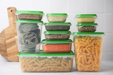 Plastic containers filled with food products on white table near tiled wall