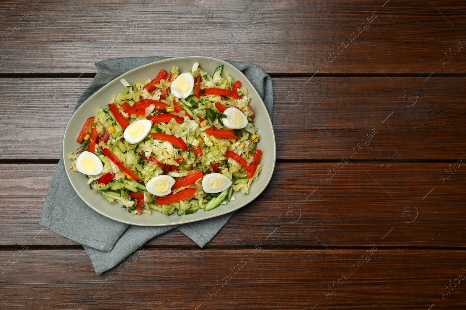 Photo of Plate of delicious salad with Chinese cabbage and quail eggs on wooden table, top view. Space for text