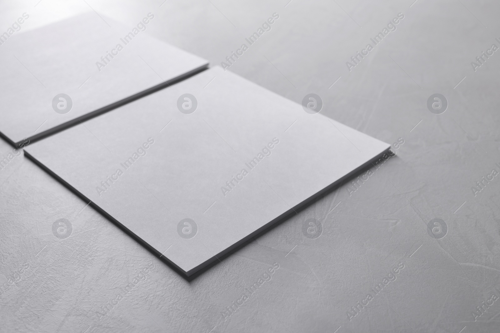 Photo of Blank paper sheets on grey textured table, closeup. Mockup for design