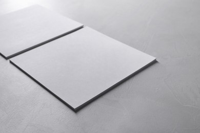 Photo of Blank paper sheets on grey textured table, closeup. Mockup for design