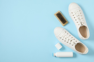 Flat lay composition with stylish footwear and shoe care accessories on light blue background, space for text