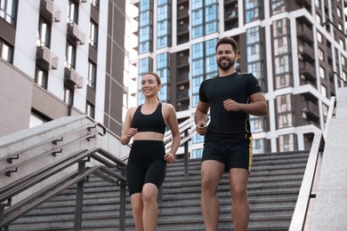 Healthy lifestyle. Happy couple running on steps outdoors, low angle view