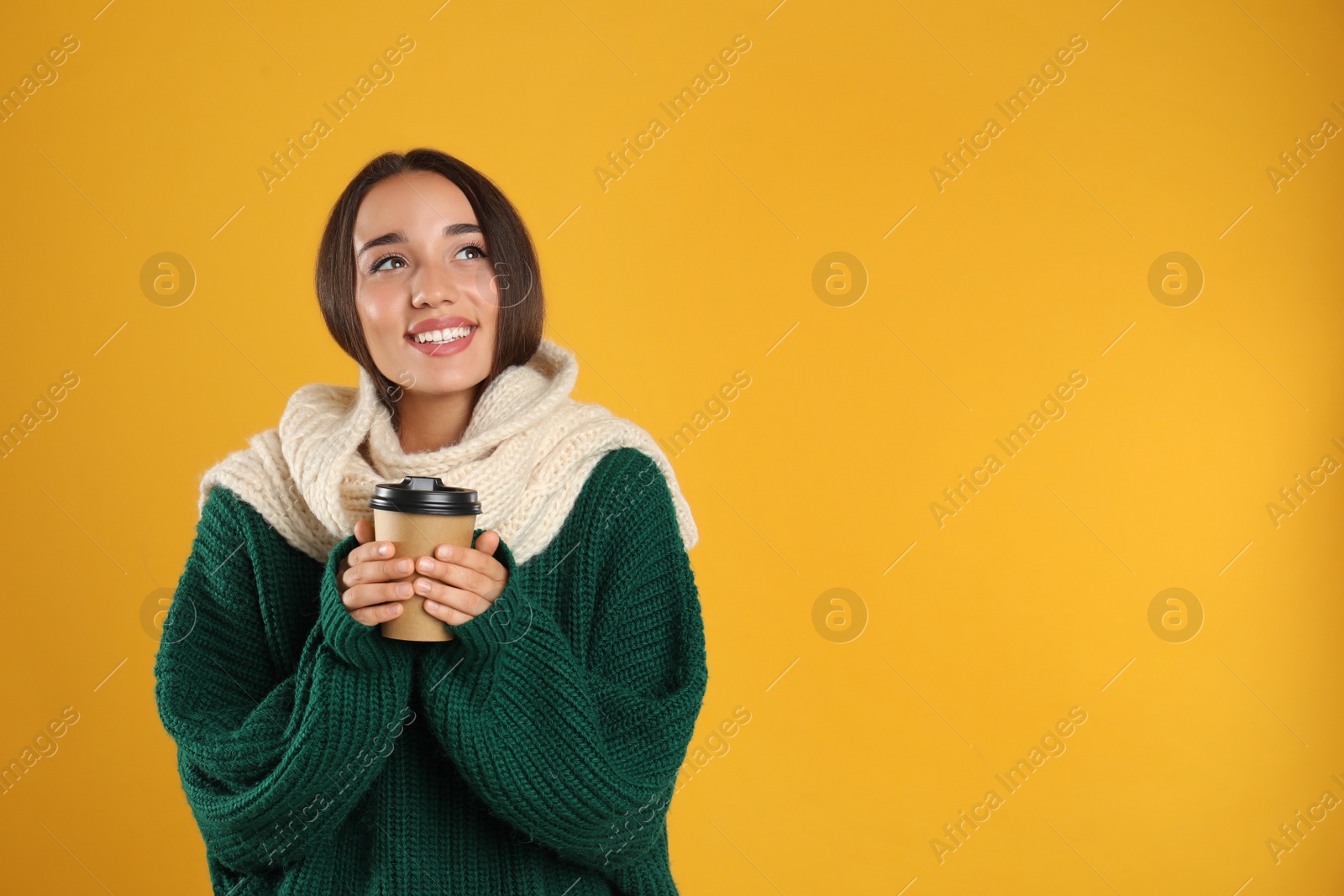 Photo of Happy beautiful woman with paper cup of mulled wine on yellow background. Space for text