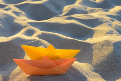 Photo of Two colorful paper boats on sand outdoors