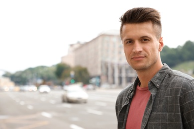 Portrait of handsome young man on city street. Space for text