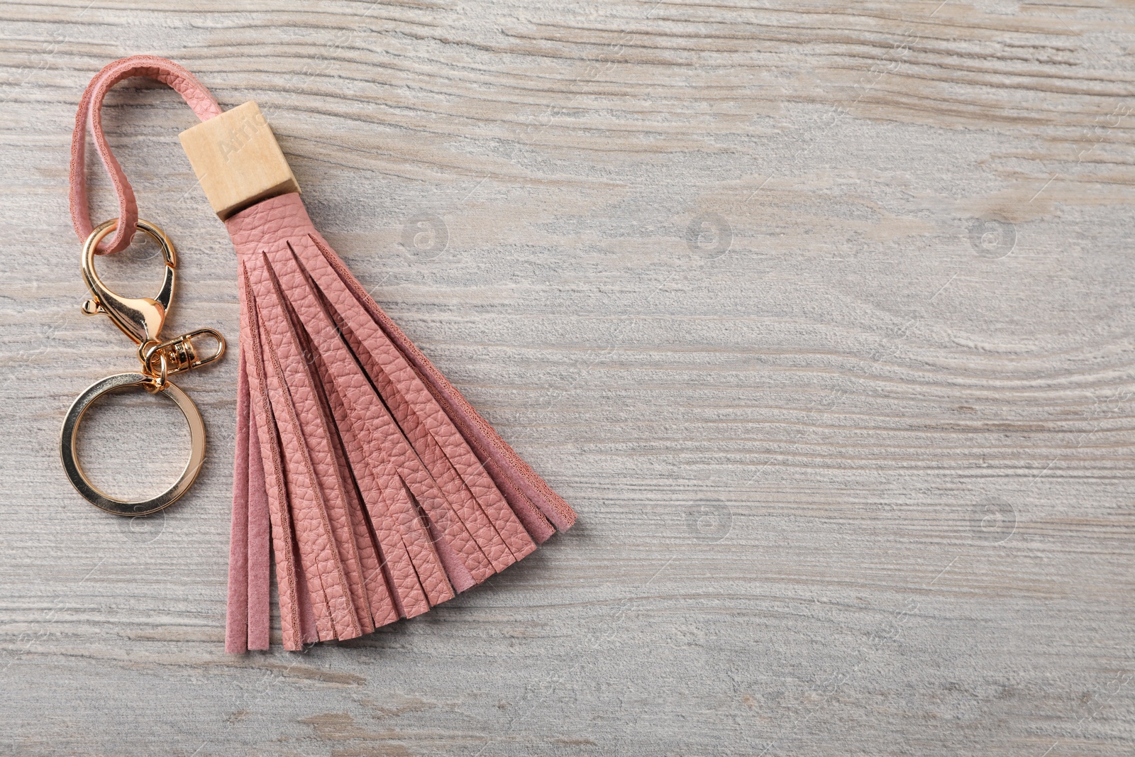 Photo of Pink leather keychain on light wooden background, top view. Space for text