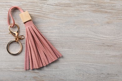 Pink leather keychain on light wooden background, top view. Space for text