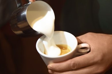 Barista preparing fresh aromatic coffee on black background, closeup